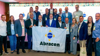 Representantes da CEASA/RS e de outras centrais de abastecimento reunidos em evento da ABRACEN. O grupo posa para foto em frente a um painel com os logotipos da CEASA e da ABRACEN, segurando uma bandeira com o nome da associa&ccedil;&atilde;o